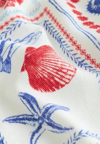 Tissu blanc avec des imprimés de coquillages rouges et d'étoiles de mer bleues, souligné par des motifs de bordures décoratives rouges et bleues.