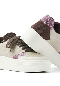 Beige Wildlederschuhe mit dunkelbraunen und lila strukturierten Akzenten, runden Schnürsenkeln und einer dicken weißen Plattformsohle.