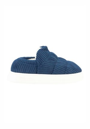 Zapato slip-on de pana color navy con suela de goma blanca, que presenta un patrón texturizado y acolchado, y una entrada elástica para facilitar su uso.