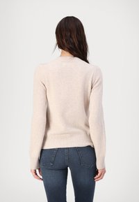 Jasno beżowy sweter dzianinowy z długimi rękawami, prążkowanymi mankietami i dołem, z okrągłym dekoltem oraz drobną, miękką teksturą.