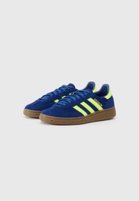 Blå ruskindssneakers med tre neongule striber, rund tå og gummisul. Har snørebånds lukning og polstret krave.