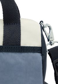 Compact bag featuring a mix of white, navy, and blue materials, with woven texture, a clip hardware, and reinforced stitching details.