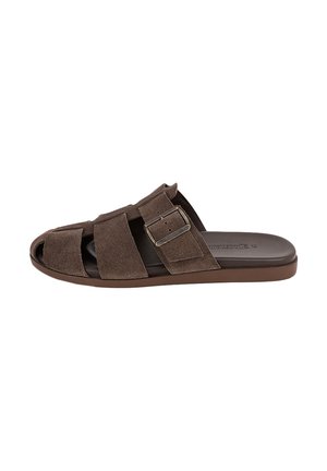 Sandale mule en daim marron à bout ouvert, avec de larges brides et une boucle métallique sur une semelle plate, orientée vers la gauche.