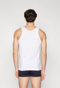 Débardeur blanc en coton doux, avec un col rond et de larges bretelles, associé à un short en boxeur bleu marine.
