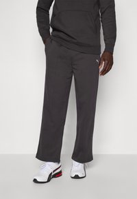 Kulgrå sweatpants lavet af en bomuldsblanding, med en afslappet pasform, sidelommer og subtile syede detaljer. Kombinationen med hvide sneakers.