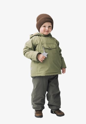 Kind trägt eine hell olivgrüne Kapuzenjacke mit einer Fronttasche, kombiniert mit dunkelgrünen Hosen und braunen Stiefeln, dazu eine braune gerippte Mütze.