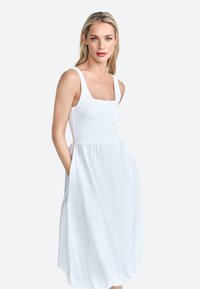 Witte, zonder mouwen jurk met een vierkante halslijn en een elastische top. Vloeiende rok met zijzakken en een gladde, lichte stoftextuur.