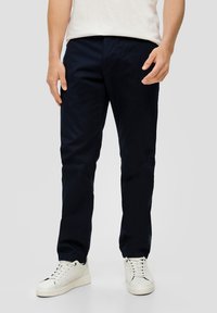 Marineblauwe, rechte chino-broeken van katoen, met een gladde textuur en zijzakken. Gedragen met witte sneakers.