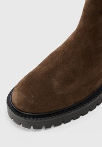 Bruna mockaskinnsankelboot med rund tå och strukturera svart gummisula med ett mönster för bra grepp.