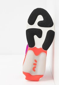 Sneaker sole featuring a patterned black rubber outer, white midsole, and vibrant orange accents with logo detail, viewed from beneath.