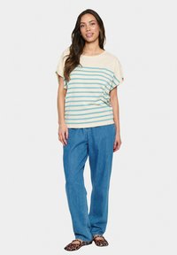 Camisa de manga corta a rayas en beige y verde azulado, combinada con pantalones de pierna ancha azules. El calzado presenta un estampado de leopardo. Textura suave.