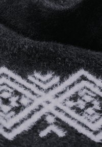Zwart stof met een zachte, fuzzy textuur, voorzien van een wit geometrisch patroon. Het ontwerp bevat diamant- en chevronvormen.