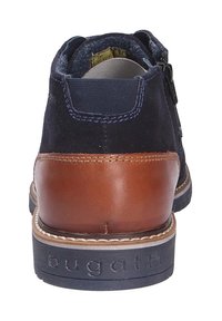 Pantof marin din suede, cu toc din piele maro, vârful rotunjit și cusături contrastante. Dispune de un fermoar lateral și o talpă din cauciuc cu logo.
