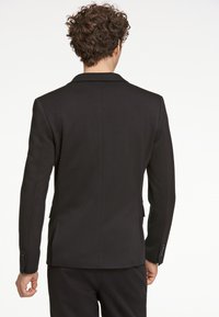 Schwarzer Blazer mit taillierter Passform, glatter Textur, Spitzenrevers und knöpfbaren Manschetten, mit Rückenschlitzen für mehr Bewegungsfreiheit.