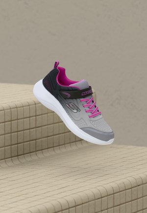 Szaro-czarny sneaker Skechers z różowymi sznurówkami i wewnętrzną wyściółką, unoszący się nad beżowymi kafelkowanymi stopniami.