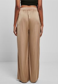 Wijd gevallen broeken in beige, met een soepele, satijnachtige textuur en een elastische tailleband voor comfort. Eenvoudig ontwerp, zonder patronen.