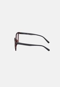 Ochelari de soare cu carapace de broască țestoasă, cu brațe negre, având un design rectangular al ramei și un finisaj texturat. Realizați din 85% plastic PET reciclat.