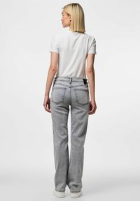 Gaiši pelēki augstās jostas vietas džinsi, kas izgatavoti no denima, ar aizmugurējām kabatām un taisnu kāju dizainu. Apvienoti ar vienkāršu baltu T-kreklu.