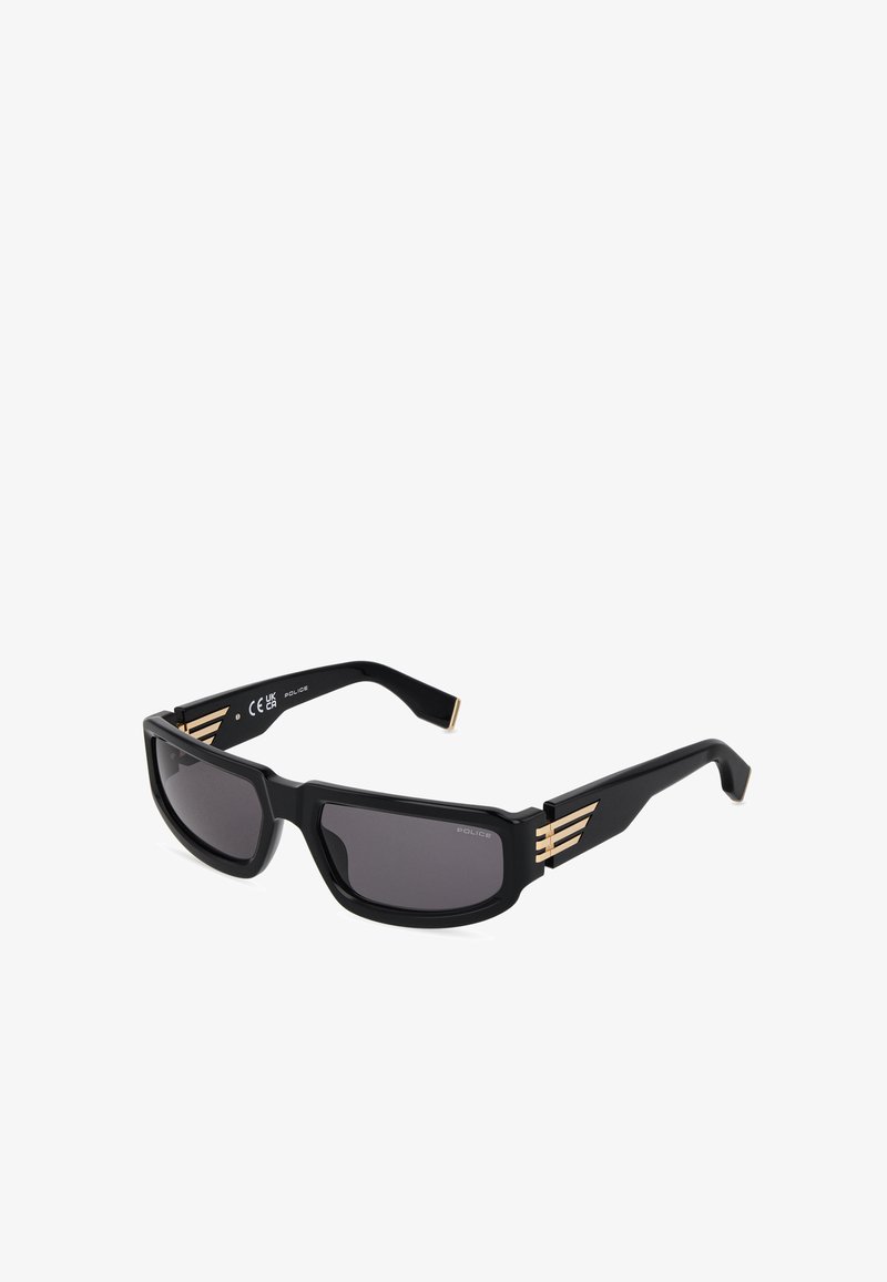 Lunettes de soleil rectangulaires noires avec verres foncés et accents rayés dorés sur des branches épaisses, affichées sur fond blanc.