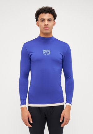 Maglia a maniche lunghe in tessuto blu brillante con una superficie liscia, caratterizzata da un logo bianco al centro e un'orlo color crema.
