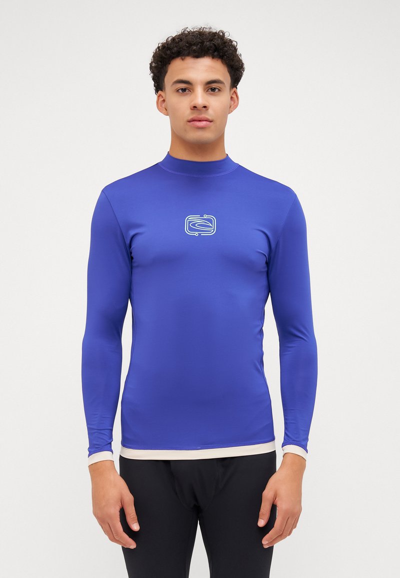 Langermet rash guard i lys blått stoff med en jevn tekstur, med en hvit logo i midten og en kremfarget bunn.