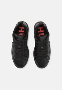 Mustat nahkakengät, joissa on sileä pinta, pyöreä kärki, mustat nauhat sekä punaiset logot yksityiskohdissa sisäpohjissa ja kielessä.