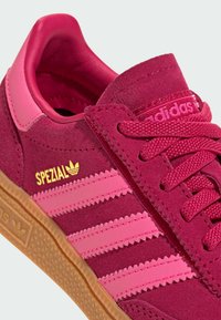 Mørkebrun semsket sneaker med pink detaljer, med tre vandrette striber, guld "SPEZIAL" branding og en tekstureret gummisål.