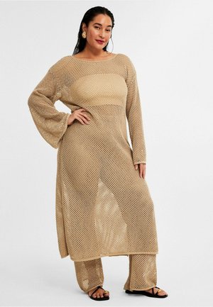 Beige mesh breisel set bestaat uit een lange mouwen top en een broek met een losse pasvorm. De textuur is open en ademend, perfect voor warm weer.