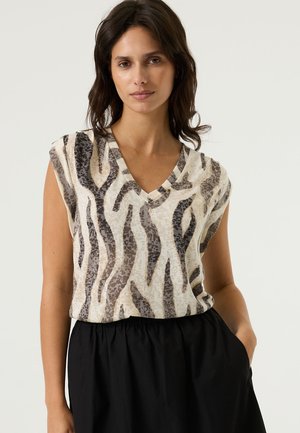 V-hals top van lichtgewicht stof met een beige en bruine dierenprint. Heeft korte mouwen en een losse pasvorm, gecombineerd met een zwarte rok.