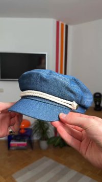 Denim cap in blue with a front peak, featuring a white rope band around the base. Soft texture, structured design, and relaxed shape.