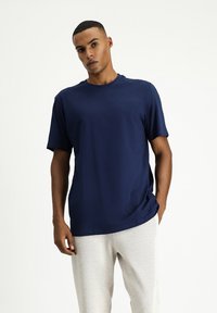 T-shirt in cotone blu navy con scollo rotondo e maniche corte, abbinato a pantaloni della tuta leggeri e texturizzati. Vestibilità semplice e rilassata.