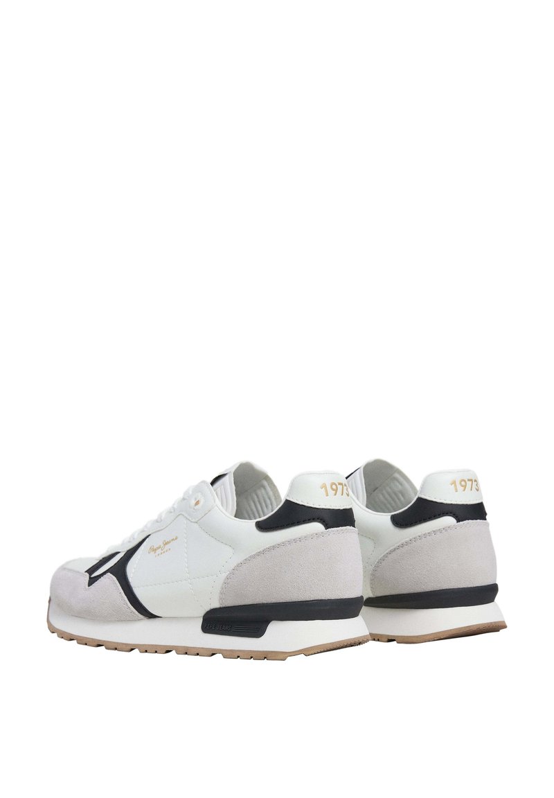 Zapatillas en blanco y gris que combinan materiales de ante y cuero, con una franja negra y el texto dorado "1973" en el talón.