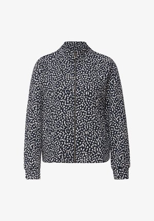 Veste zippée à motifs bleu marine et blanc avec col montant et manches longues, présentant un design abstrait tacheté.