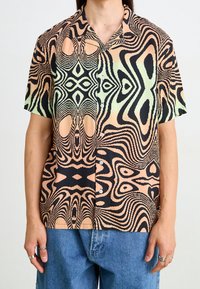 Chemise à manches courtes avec un motif abstrait en vagues noir, pêche et vert. Tissu léger avec un col et des détails de boutons.