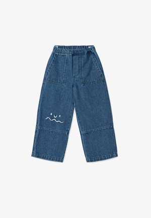 Blue denim pants with an elastic waistband, featuring a relaxed fit and a white embroidered design of a face and waves on the front.