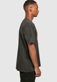 Grå oversized T-shirt med et falmet udseende, kortærmede og rund hals. Har farverig grafisk tryk på forsiden.