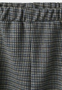 Tkanina s uzorkom houndstooth u mornarsko plavoj, bež i smeđoj boji. Ima elastičnu ureznicu i teksturirani završetak. Kvadratni oblici stvaraju poseban izgled.
