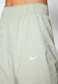 Jasnozielone szorty Nike z elastycznym pasem, teksturowanym materiałem i małym białym logo na lewym udzie.