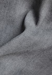 Šedá látka s hladkou texturou, obsahující jemný vzor tkaní. Materiál vypadá měkce a mírně splývá, což ukazuje hloubku barvy.