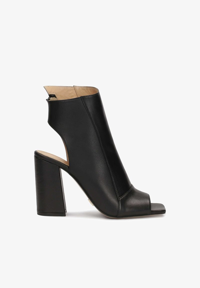 Svart läder öppen tå ankelboot med blockklack och utskärningsdesign. Slät textur, med en minimalistisk och modern form.