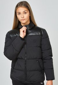 Svart pufferjacka med en glänsande svart övre del, dragkedjestängning, sidofickor och hög krage. Tyget har en slät yta.