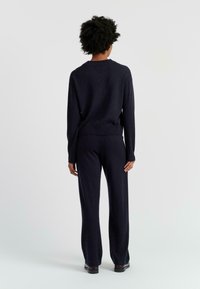 Pull en maille bleu marine et pantalon assorti en tissu doux, avec une coupe décontractée, des manches longues et des poignets et ourlet côtelés.