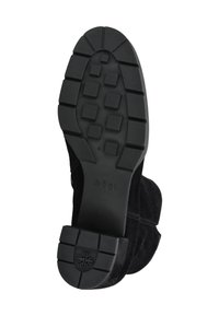 Černá podrážka boty s hlubokým čtvercovým vzorem, název značky "högl" a logo na patě, pohled zespodu na bílém pozadí.