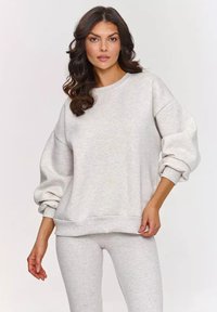 Jasnoszara bluza z okrągłym dekoltem i oversize'owymi, marszczonymi rękawami, zestawiona z pasującymi, lekkimi spodniami o miękkiej fakturze.