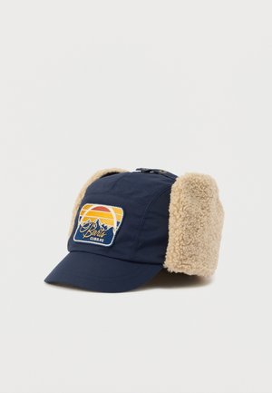 Navy cap with tan fleece ear flaps, featuring a mountain and sunset patch, designed for cold weather protection and comfort.
