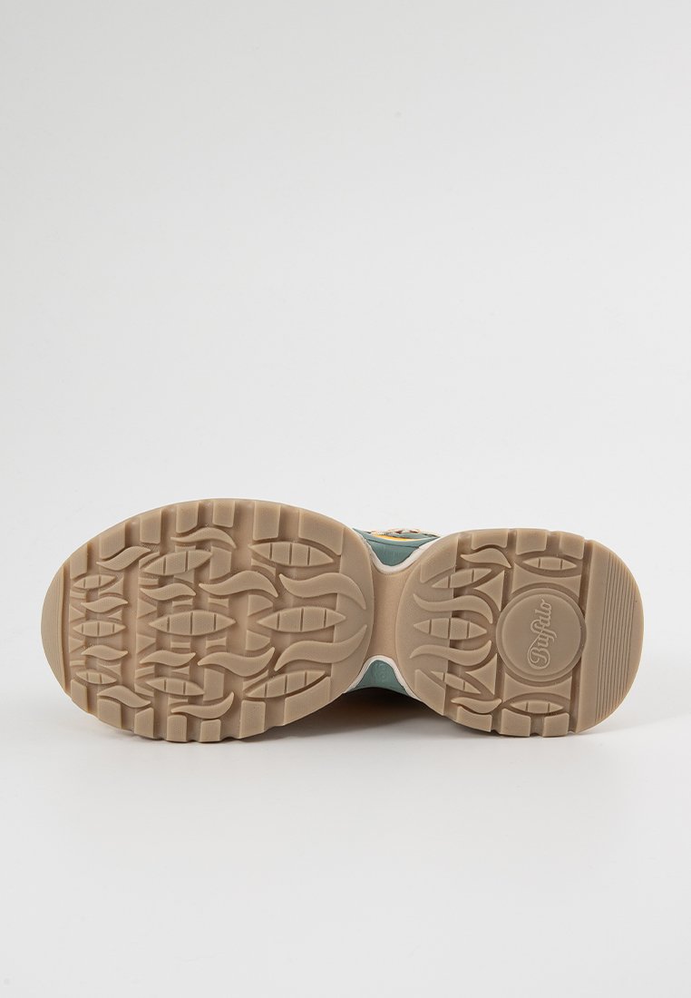 Suela de zapatilla con una banda de rodadura de goma beige que presenta patrones ondulados y rectangulares, y un logotipo redondo grabado cerca del talón.