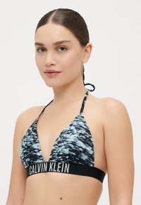 Calvin Klein zwart en blauw gestreepte bikini-top, driehoekig ontwerp met verstelbare bandjes en een logoband aan de onderkant.