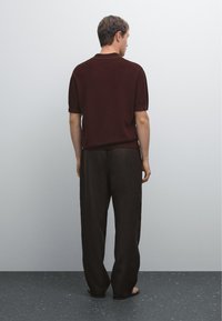 Polo shirt in magenta a maglia e pantaloni neri larghi. Texture morbida, maniche corte e colletto classico. Design semplice e minimalista.
