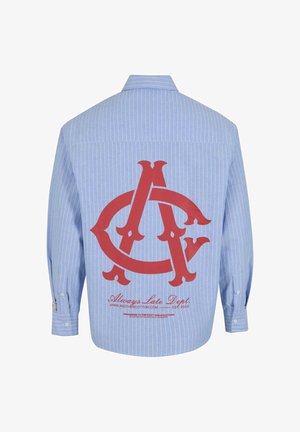 Button-up shirt in light blue with white vertical stripes. Features a large red logo and text on the back. Cotton material, long sleeves.