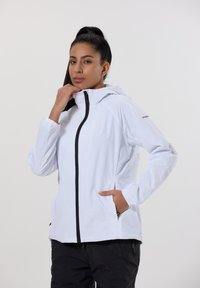 Valkoinen kevyt takki, jossa on musta vetoketju, huppu ja joustavat hihansuut. Varustettu sivutaskuilla ja rentoa muotoilua.